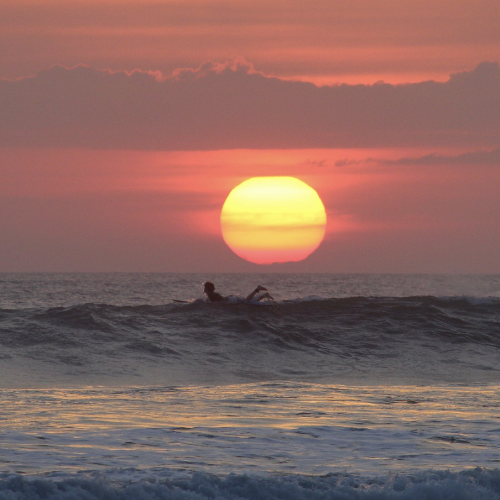 surfer en mode Pura Vida sur une planche au coucher du soleil